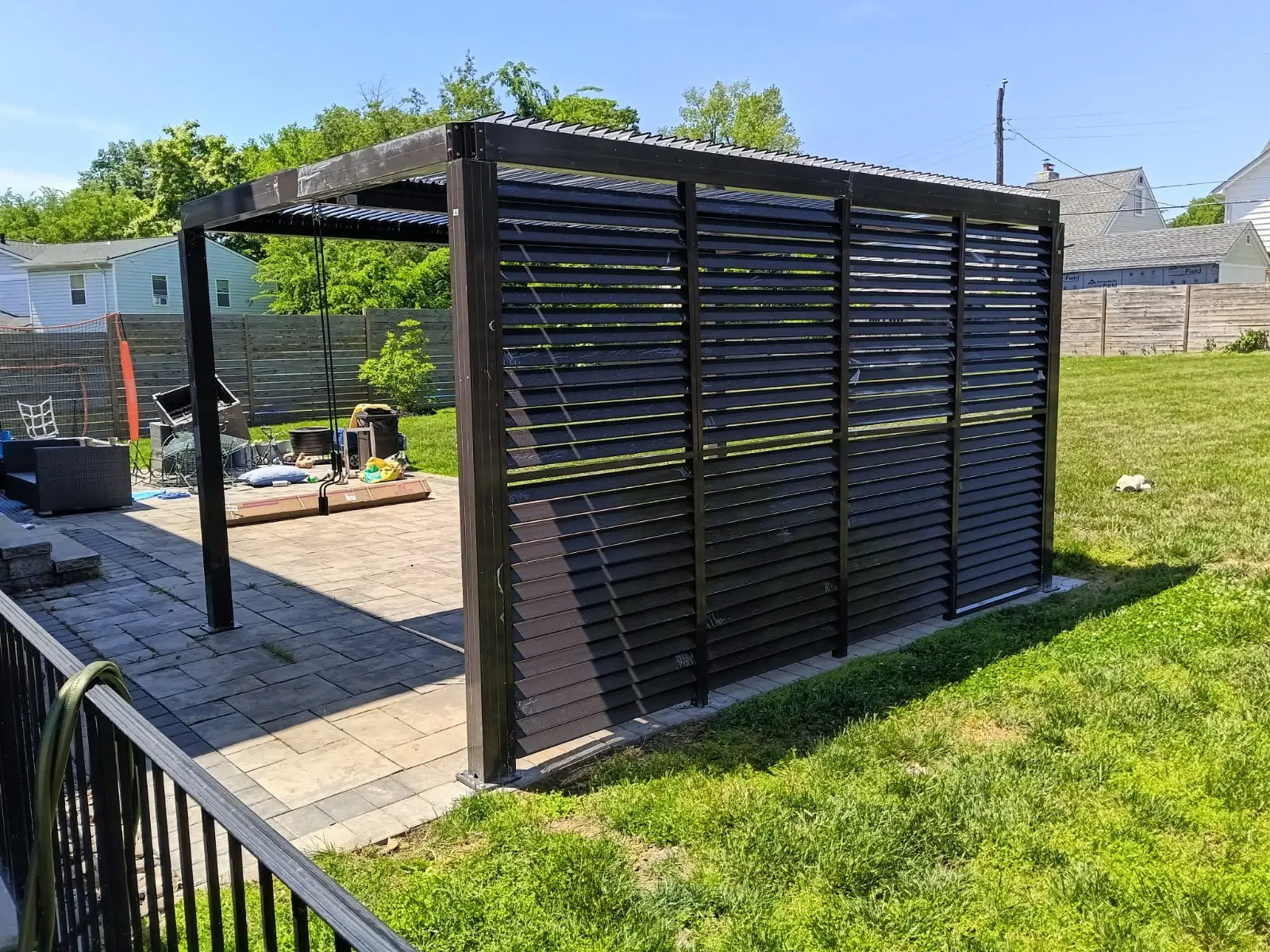 Black aluminium pergola with louvered privacy panels installed on a raised deck