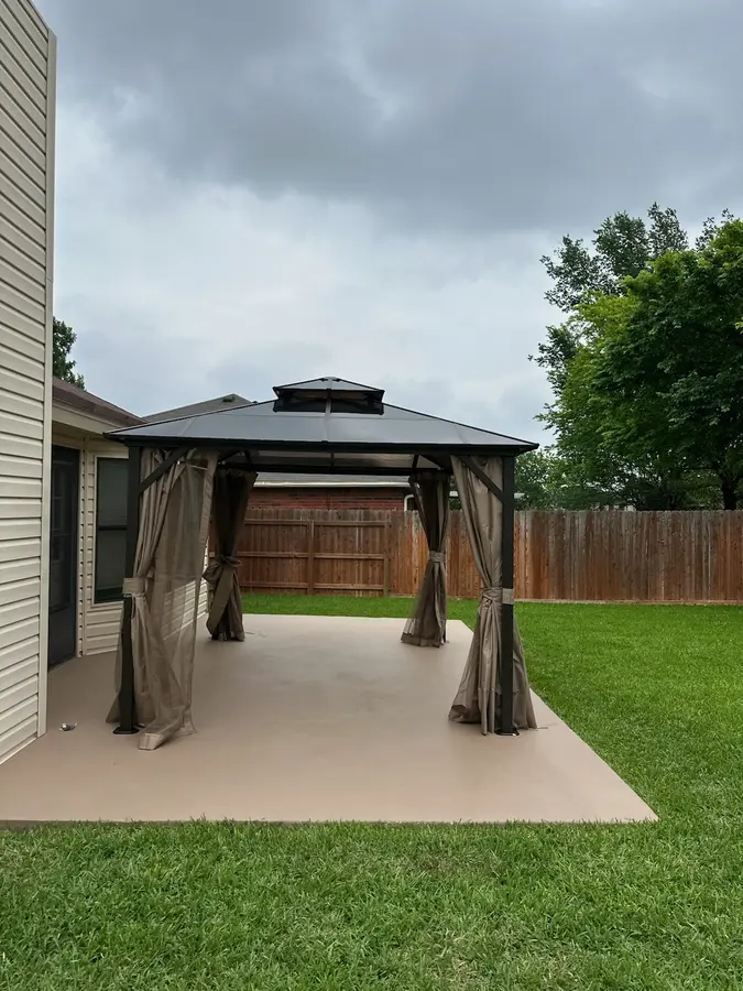 Hardtop gazebo with side curtains assembled on a back patio