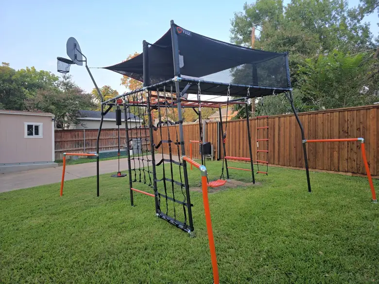 Dome climber and monkey bar set with a shade sail installed on a lawn