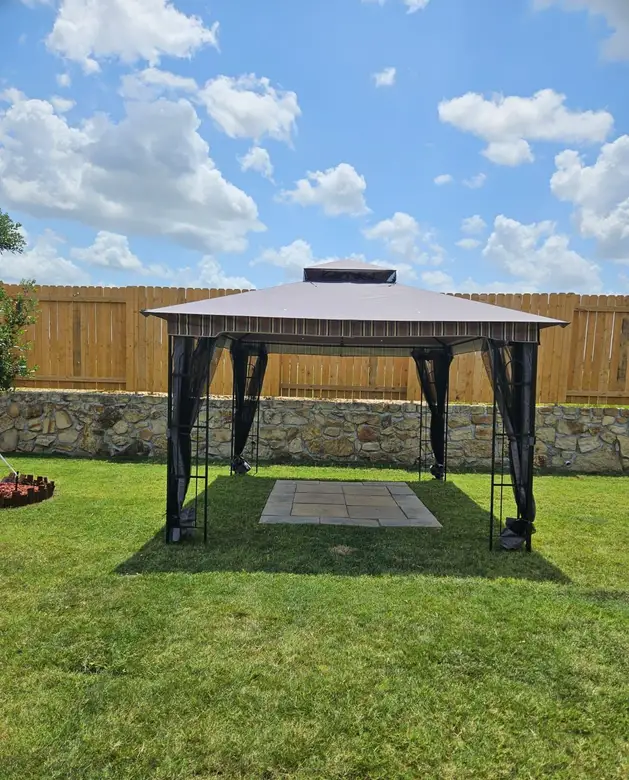 Hardtop gazebo assembled on a lawn in a fenced back yard