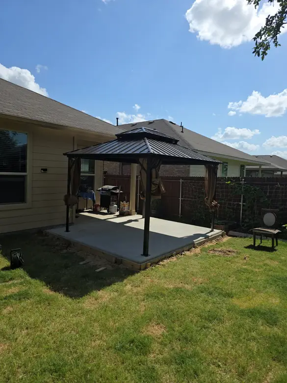 Hardtop gazebo installed on a back patio seen across the lawn