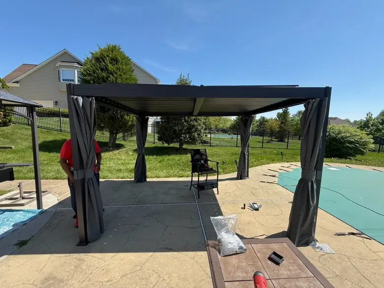 Louvered pergola with curtains going up beside a swimming pool