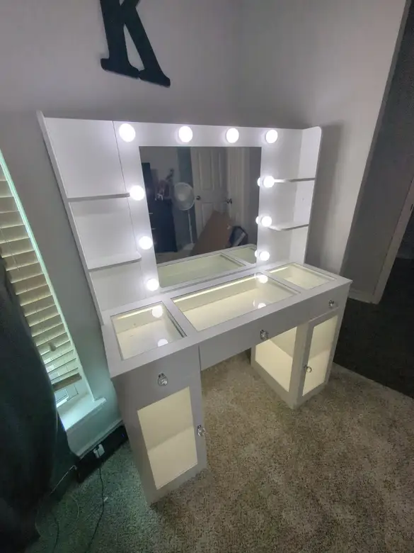 Lighted vanity desk and mirror assembled against a bedroom wall